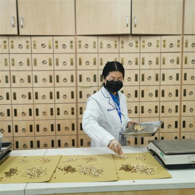 　侯惠鳴為顧客抓藥。